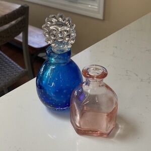 Two Glass perfume bottles with one sun top.
